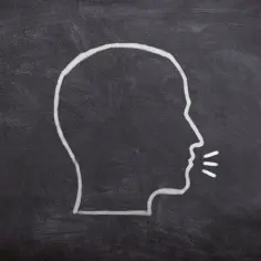 Kredą na tablicy narysowano profil głowy z wypowiadanymi słowami. Ilustracja do rozbioru gramatycznego zdania.