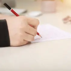 Dłoń z ołówkiem wypełnia arkusz testowy. Szybka nauka na sprawdzian w godzinę jest możliwa!
