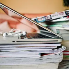 Laptop i stosy książek, słuchawki. Czy warto wybrać liceum eksternistyczne? Nauka w domowym zaciszu.