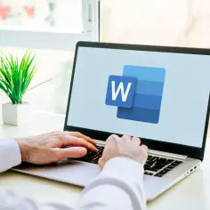 Ręce na klawiaturze laptopa z logo Word. Dowiedz się, jak usunąć tabelę w Word, by uporządkować dokument.