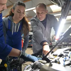 Uczniowie technikum mechanicznego pod okiem mistrza uczą się naprawiać samochód. Dowiadują się, ile trwa technikum po zawodówce, zdobywając cenne umiejętności.