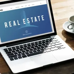 Laptop z napisem "REAL ESTATE". Czyżby to był idealista, który marzy o własnym domu?