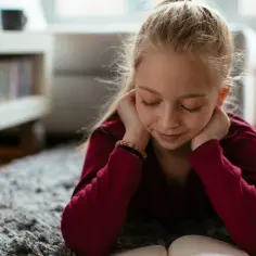 Zofia Bobrówna czyta wiersz w pamiętniku, leżąc na dywanie.