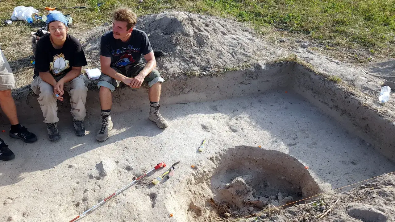Dwóch młodych ludzi na stanowisku archeologicznym. Zastanawiają się, jak zostać archeologiem, podczas gdy narzędzia czekają na odkrycia.