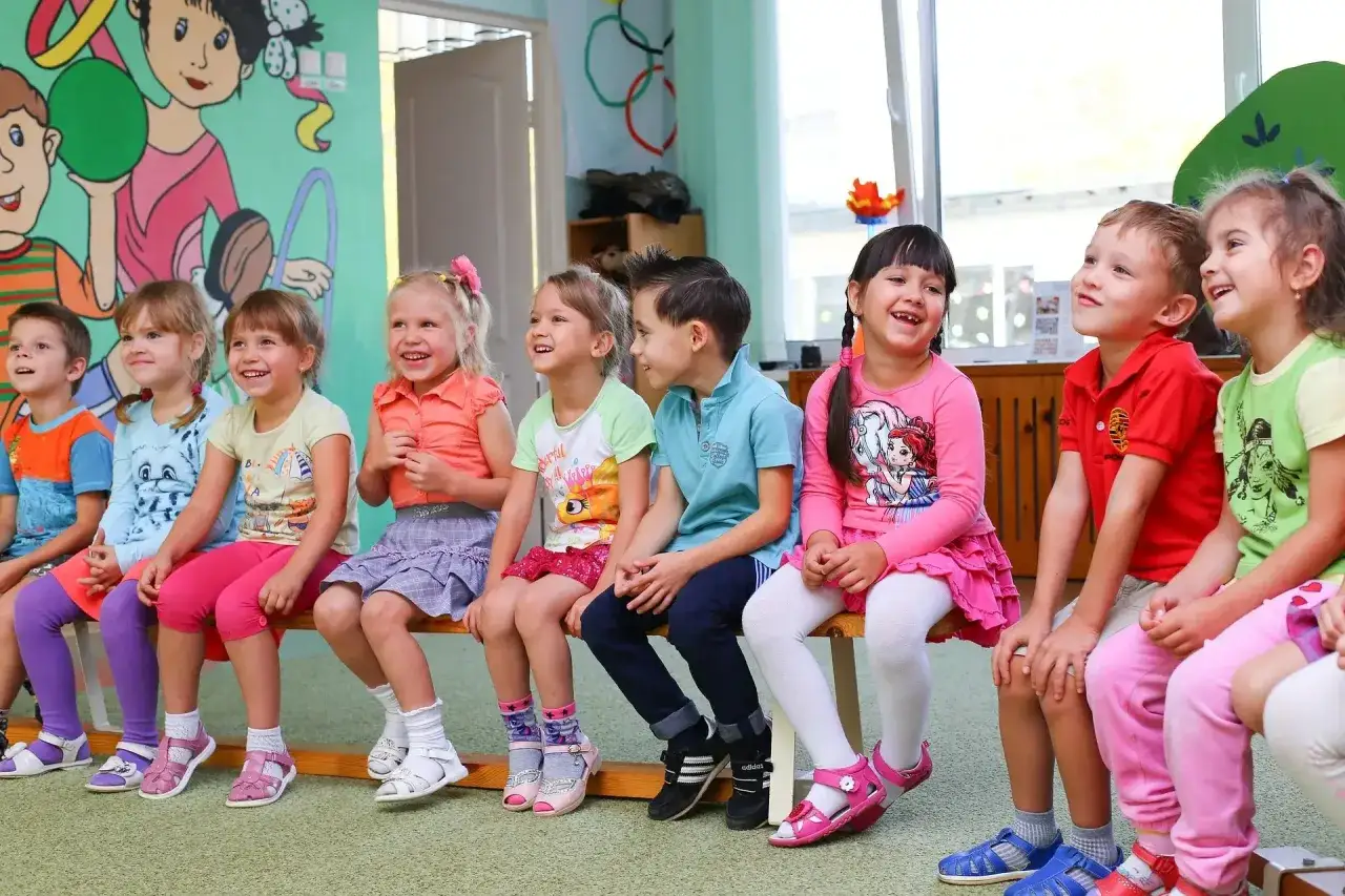 Uśmiechnięte dzieci siedzą w przedszkolu, zastanawiając się, czy zerówka jest obowiązkowa.